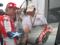 Nicky Hayden signing a photo in benefit of Riders for Health at Laguna day of champions